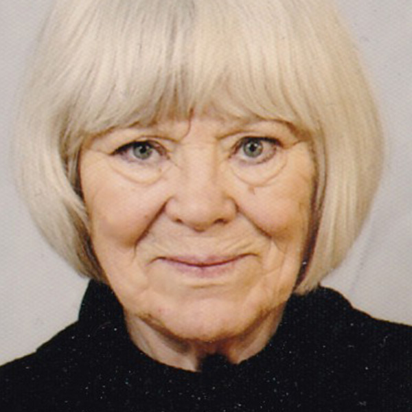 Portrait of an individual with light-colored hair wearing a dark textured top against a neutral background, conveying a calm and composed atmosphere connected to the artistic work and life story of Monika Johannisson.